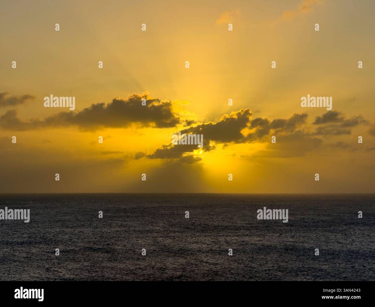 Caribbbean sunset over water with sun rays shining through the clouds - Smartphone Captured Stock Image