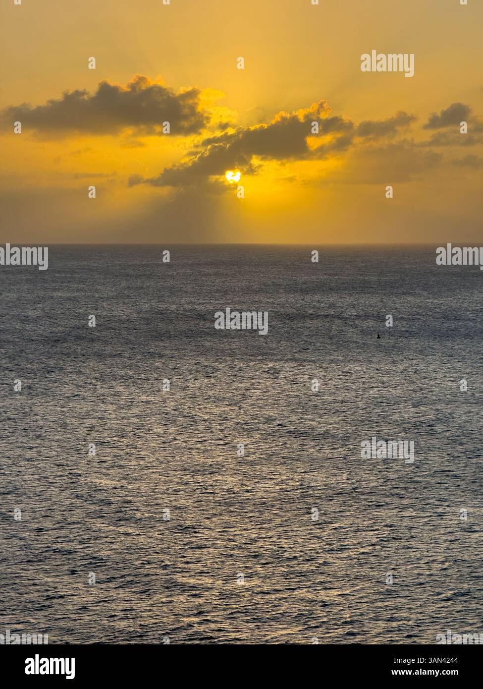 Caribbbean sunset over water with sun rays shining through the clouds - Smartphone Captured Stock Image