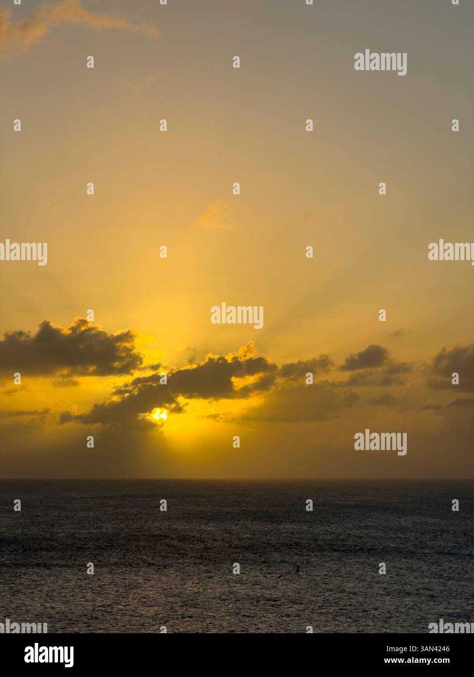 Caribbbean sunset over water with sun rays shining through the clouds - Smartphone Captured Stock Image
