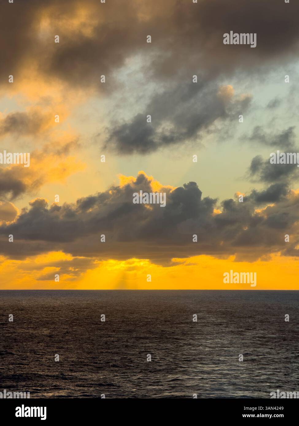 Caribbbean sunset over water with sun rays shining through the clouds - Smartphone Captured Stock Image