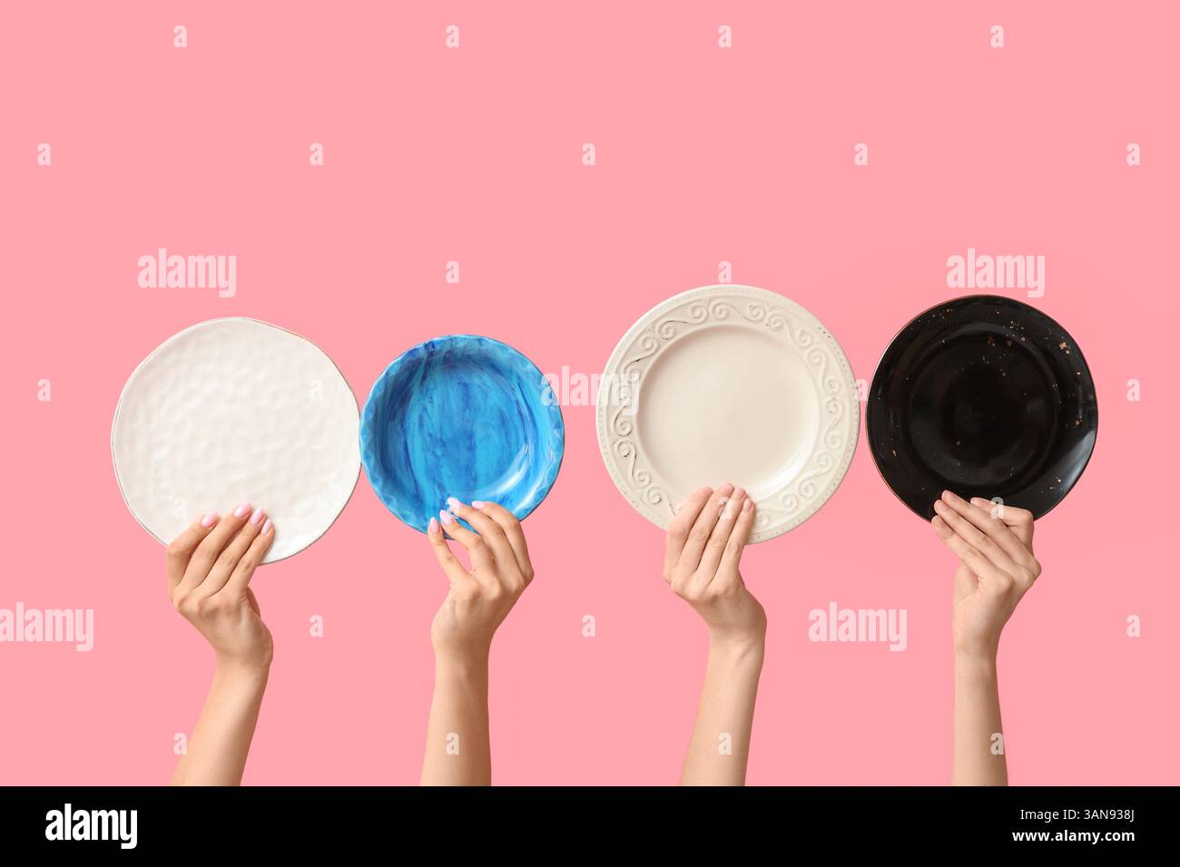 Hands holding empty plates on pink background Stock Photo