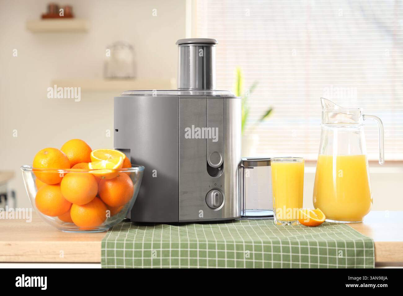 Modern juicer with oranges on table in kitchen Stock Photo