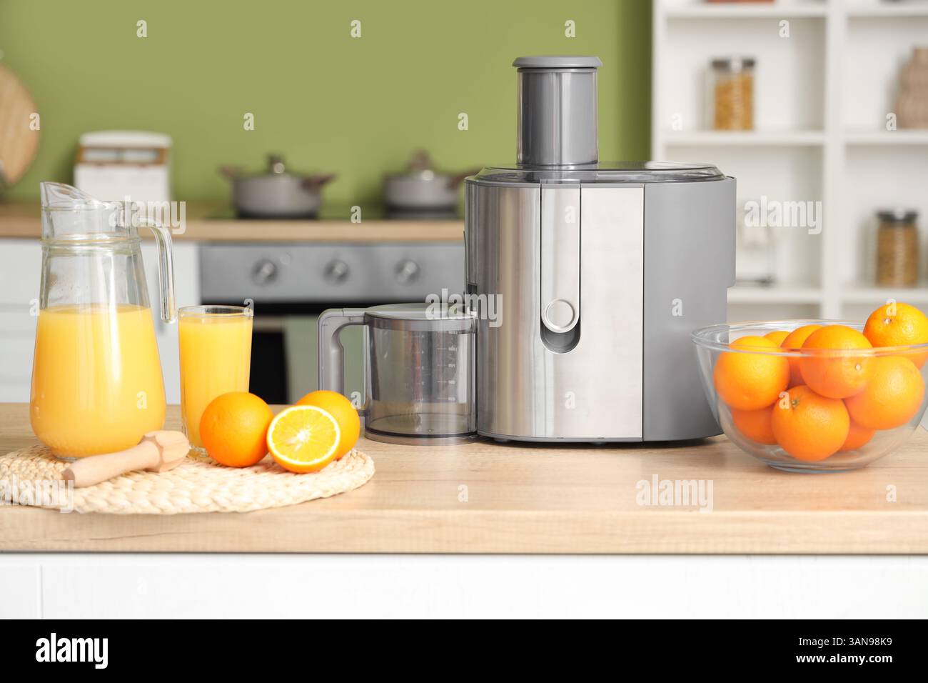 Modern juicer with fresh oranges on table in kitchen Stock Photo
