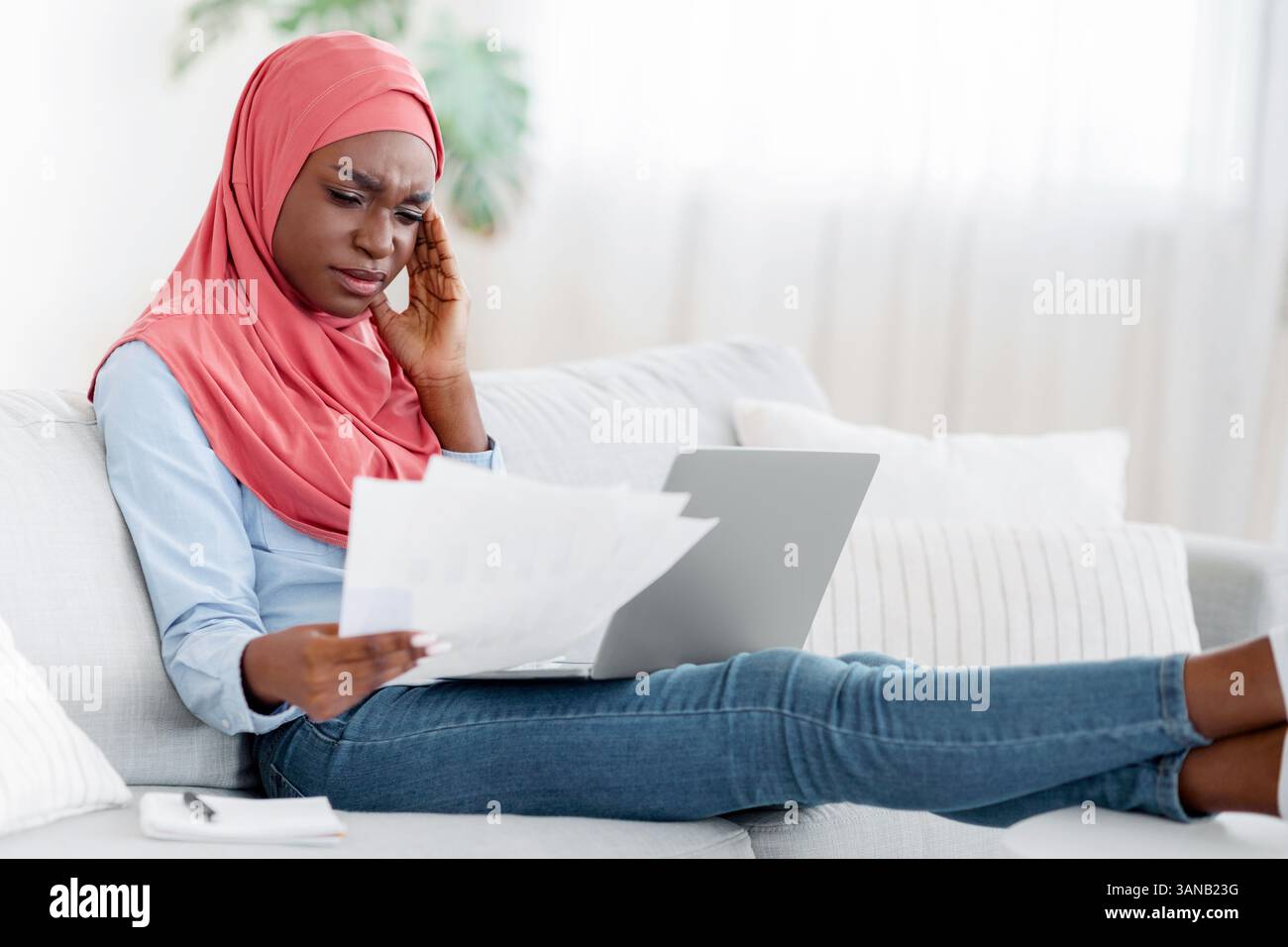 Black Muslim Lady Having Headache While Working Remotely With Papers At Home Stock Photo