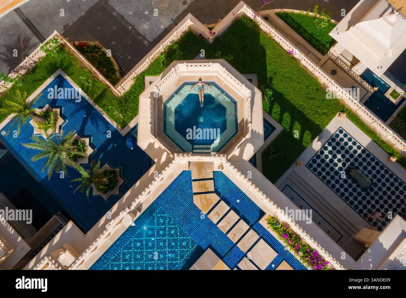 Aerial view of a woman relaxing in a swimming pool in a luxury hotel in ...