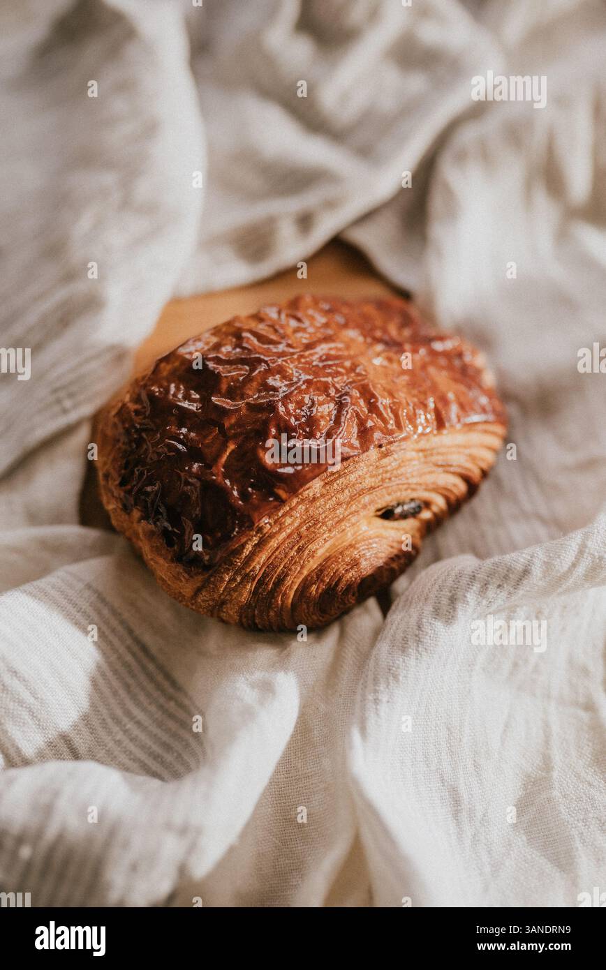 A piece of bread with a brown crust sits on a white cloth. The bread is ...