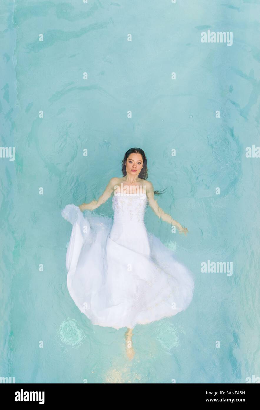 Aerial view of a beautiful woman in wedding dress floating in clear ...