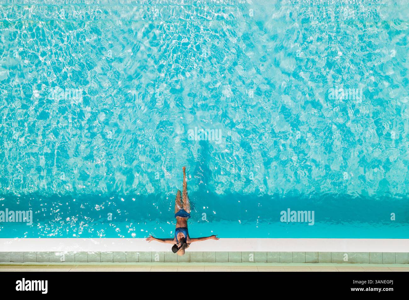 Aerial view of a blonde woman relaxing along the swimming pool of a ...