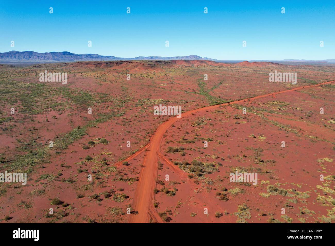 Aerial view of rugged desert landscape with red earth and a winding ...