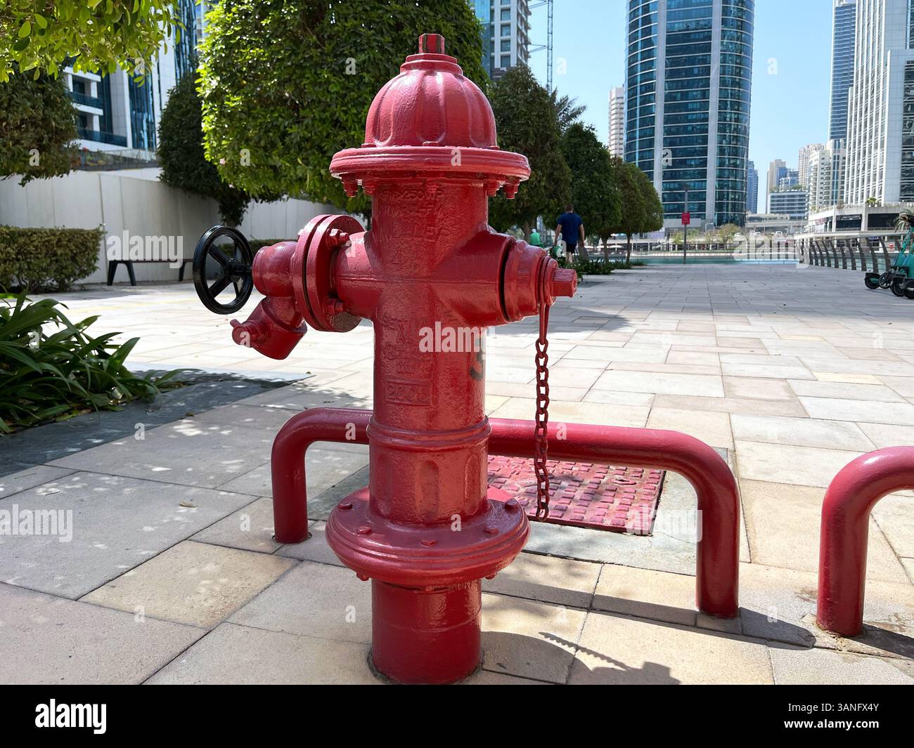 Hydrant Rise A red fire hydrant installed on a city sidewalk with high-rise ...