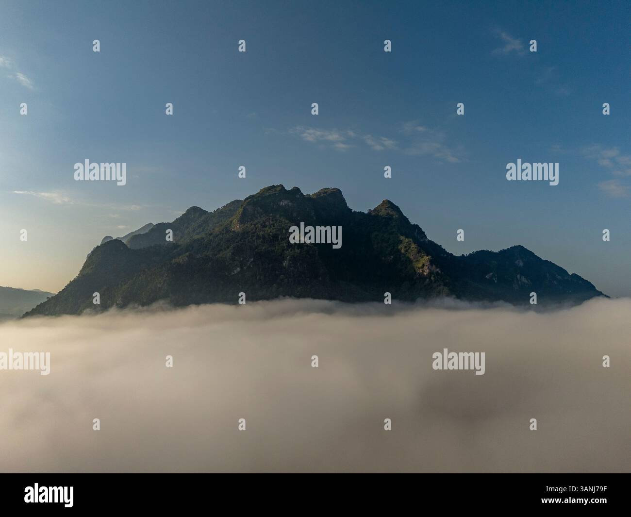 Aerial view of majestic mountains shrouded in fog under a serene sky ...