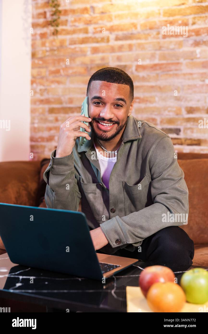 Smiling freelancer working from home and talking on phone Stock Photo