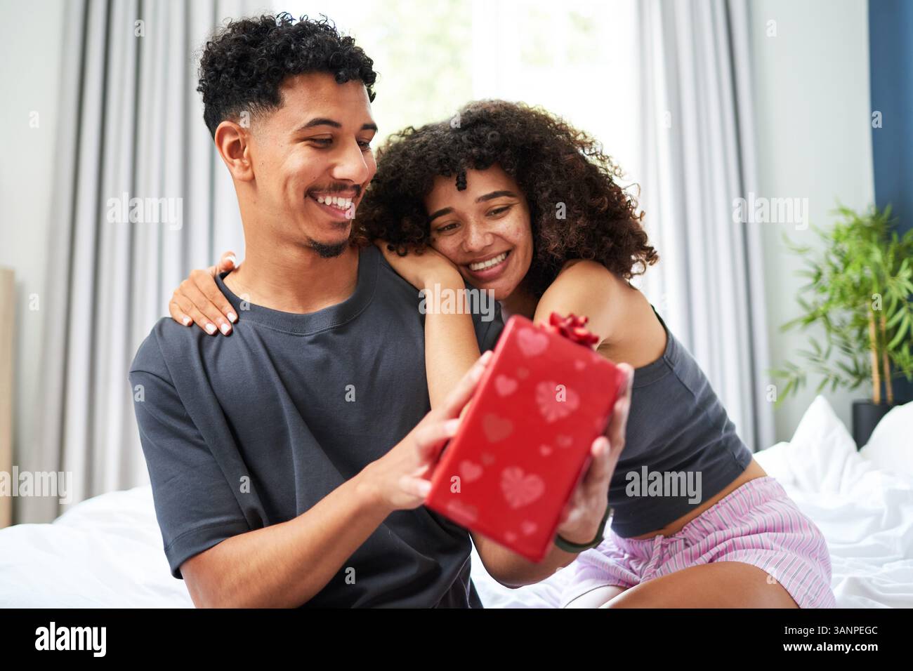 Smiling Couple Sharing a Gift Together in a Cozy Home Environment Stock Photo