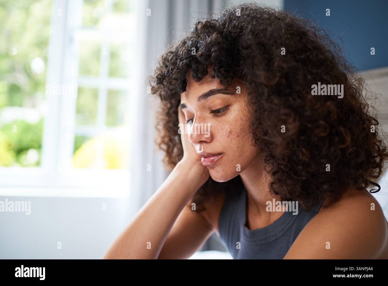Portrait of a Thoughtful Young Woman at Home Amidst Natural Lighting Stock Photo