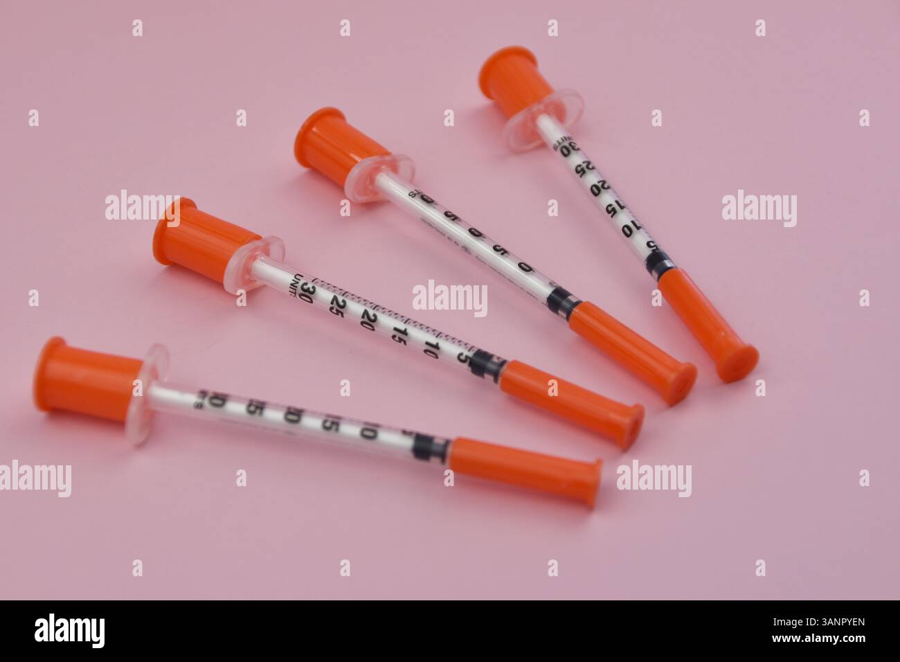 Plastic syringes arranged on soft pink backdrop, detailed macro shot of ...