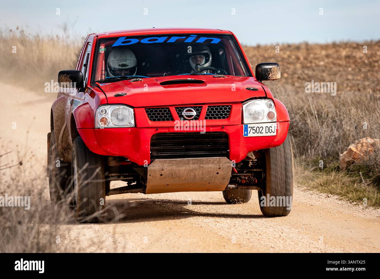 Madrid, Spain; 02-15-2025: Red Nissan Navara truck charges through a rugged rally raid, blasting dust and demonstrating power and endurance on the off Stock Photo