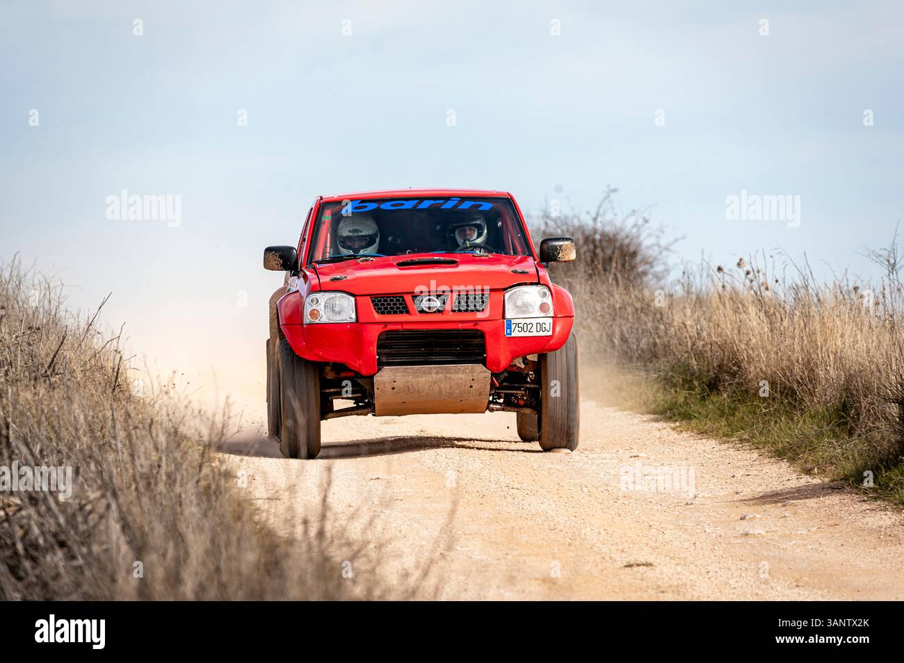 Madrid, Spain; 02-15-2025: Red Nissan Navara truck charges through a rugged rally raid, blasting dust and demonstrating power and endurance on the off Stock Photo