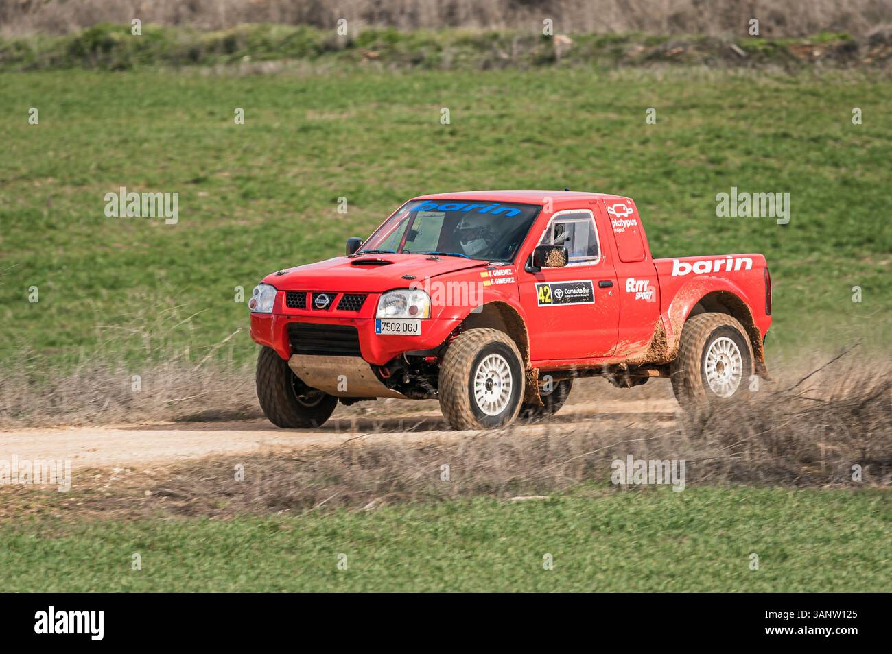 Madrid, Spain; 02-15-2025: Red Nissan Navara truck charges through a rugged rally raid, blasting dust and demonstrating power and endurance on the off Stock Photo
