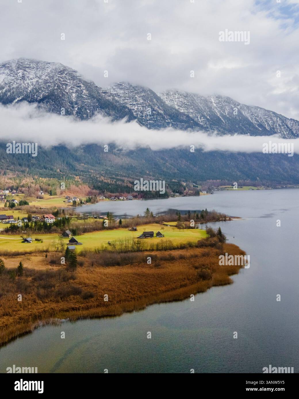 Aerial view of tranquil Hallstatter See surrounded by picturesque mountains and a serene village under low clouds, Bad Goisern, Austria. Stock Photo