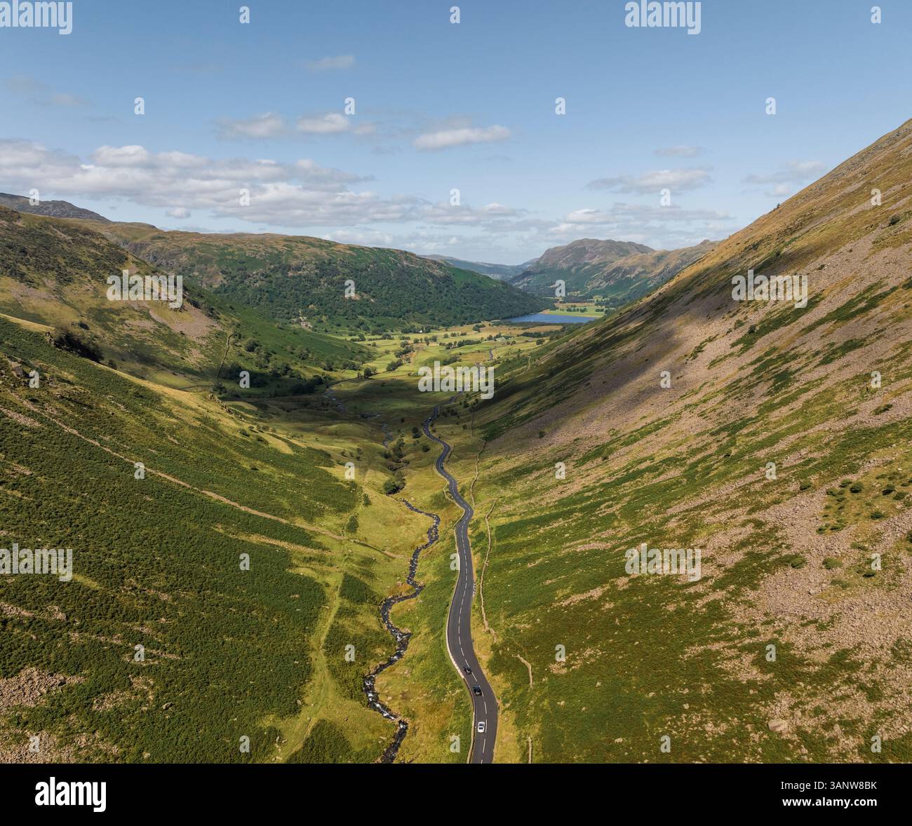 Aerial view of winding road through lush valley and majestic mountains ...