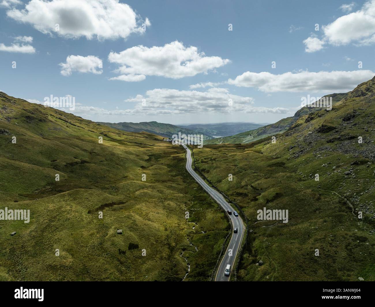 Aerial view of winding road through serene valley and majestic ...