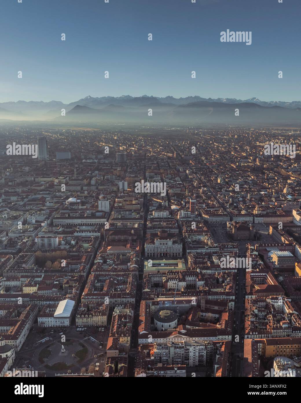Aerial view of Turin downtown in evening haze at sunset with the Alps ...