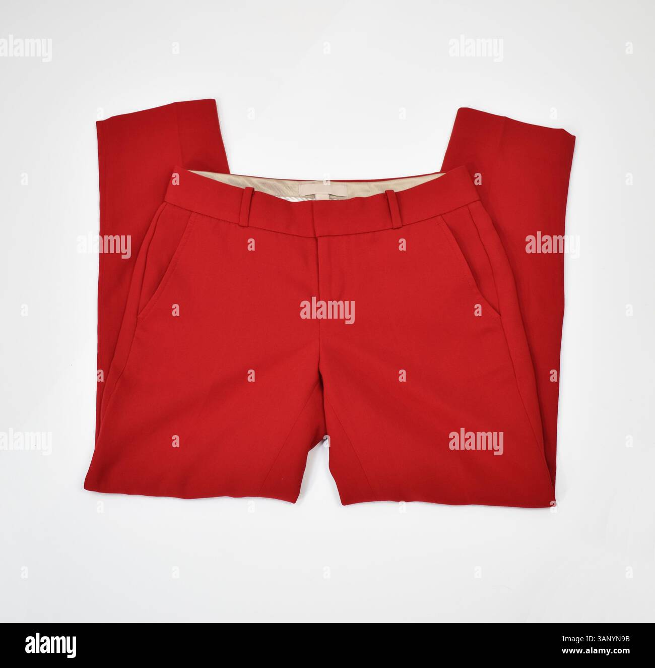 Red tailored dress pants folded on plain white surface elegant office ...
