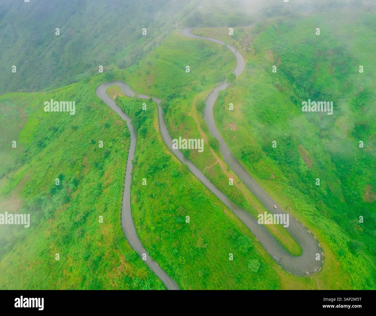 Aerial view of a beautiful winding mountain road through lush green ...