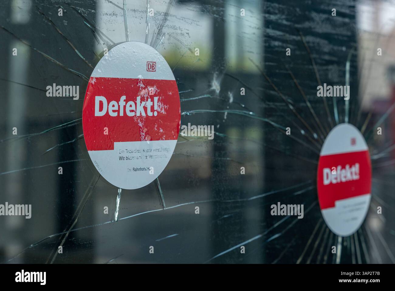 Zerbrochene Glasscheibe mit Defekt-Hinweis der Deutschen Bahn 15.04.25, Limburg: Symbolfoto, Illustrationsbild, Symbolbild, Illustrationsfoto, Alltagsszene Zwei zerbrochene Scheiben an einem Bahnhof oder Wartehäuschen, gekennzeichnet mit einem Aufkleber der Deutschen Bahn mit dem Hinweis Defekt. Die Risse verlaufen sternförmig über das Glas, was auf mutwillige Beschädigung oder Vandalismus hindeutet. Die Szene steht exemplarisch für Infrastrukturprobleme und Sicherheitsfragen im öffentlichen Raum. . Limburg Hessen Germany *** Broken glass pane with defect Deutsche Bahn notice 15 04 25, Limburg Stock Photo