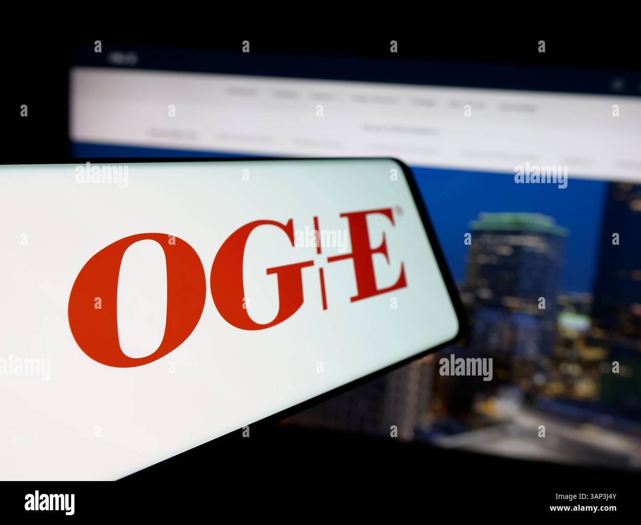 Stuttgart, Germany - 12-09-2024: Mobile phone with logo of US company Oklahoma Gas Electric Company (OGE) on screen in front of website. Stock Photo