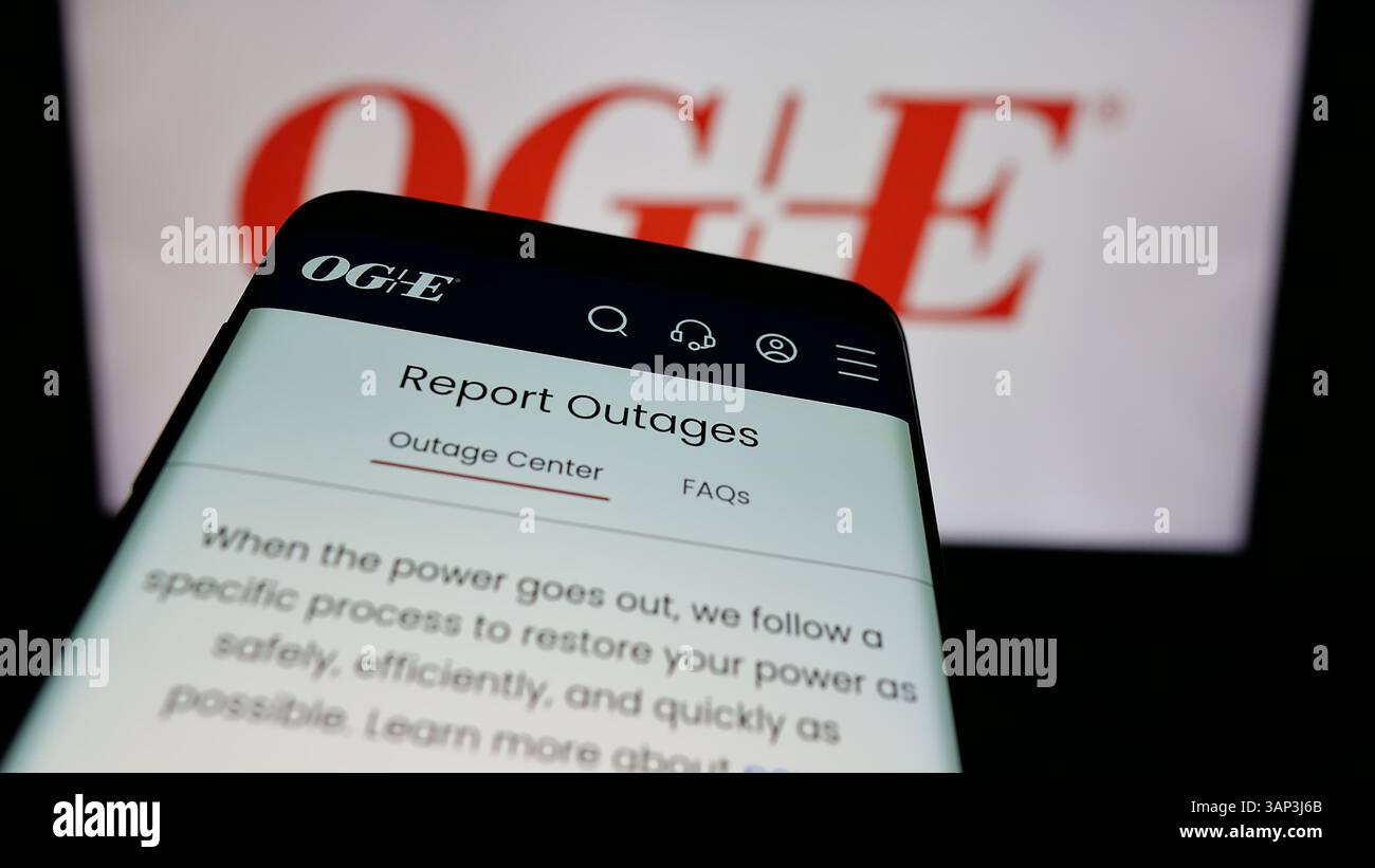 Stuttgart, Germany - 12-09-2024: Smartphone with website of US company Oklahoma Gas Electric Company (OGE) on screen in front of business logo. Stock Photo