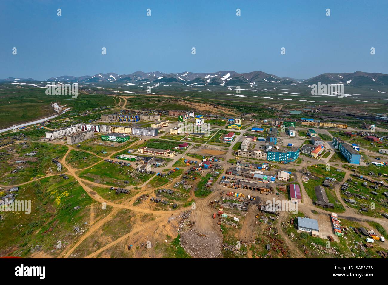 Aerial view of a rural village surrounded by mountains and greenery ...