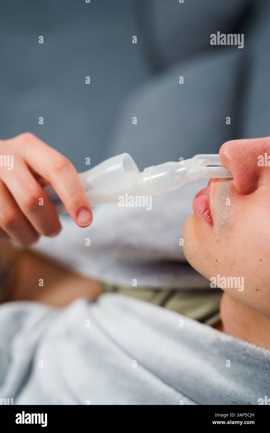 Young man with asthma attack breathing with inhaler in the bad. Doing ...