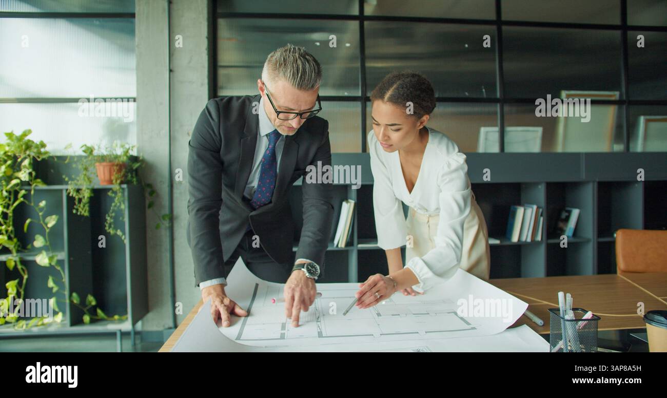 Architects reviewing blueprint in modern office space Stock Photo