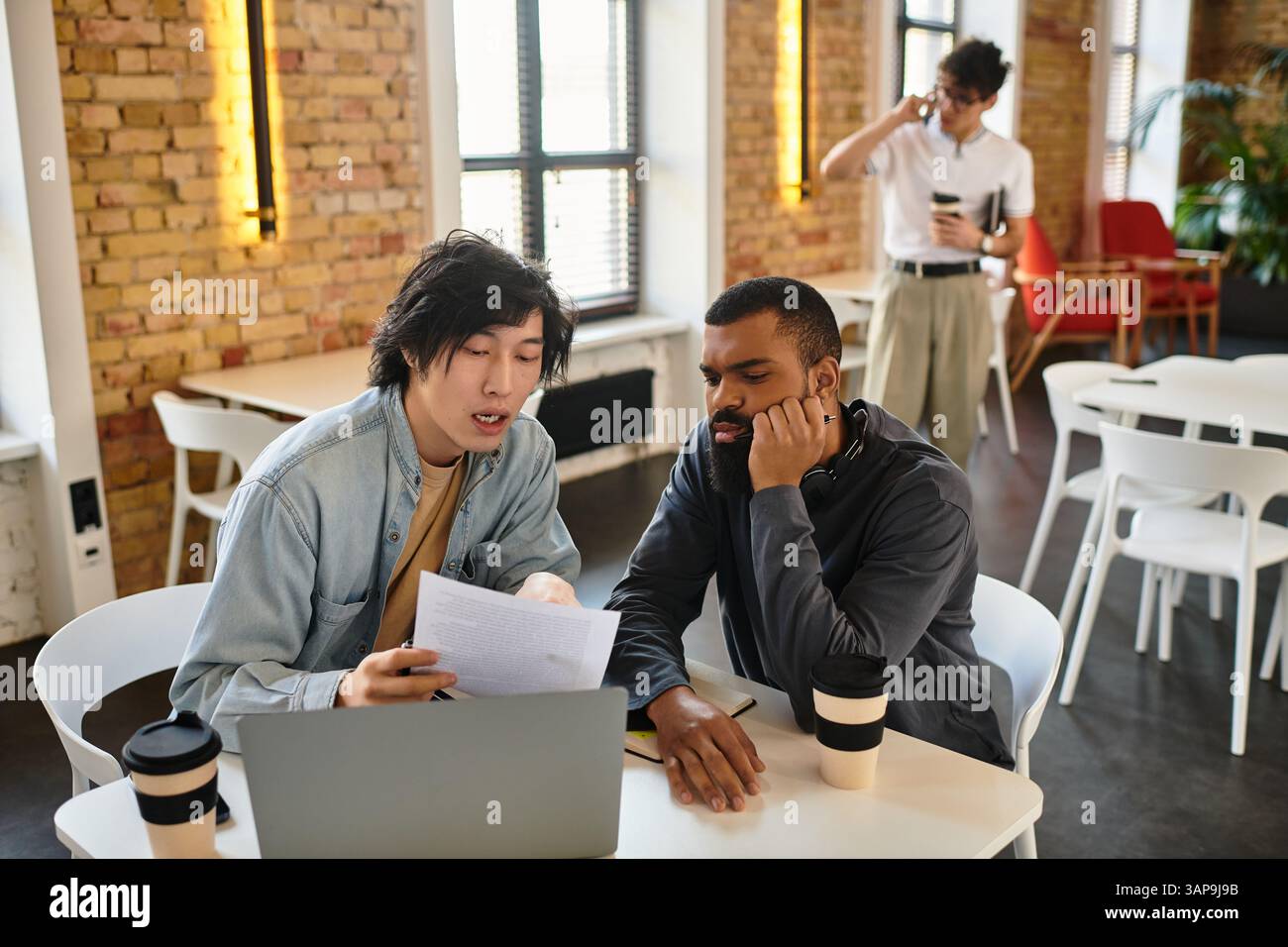 Two professionals engage in a collaborative effort while examining documents together. Stock Photo