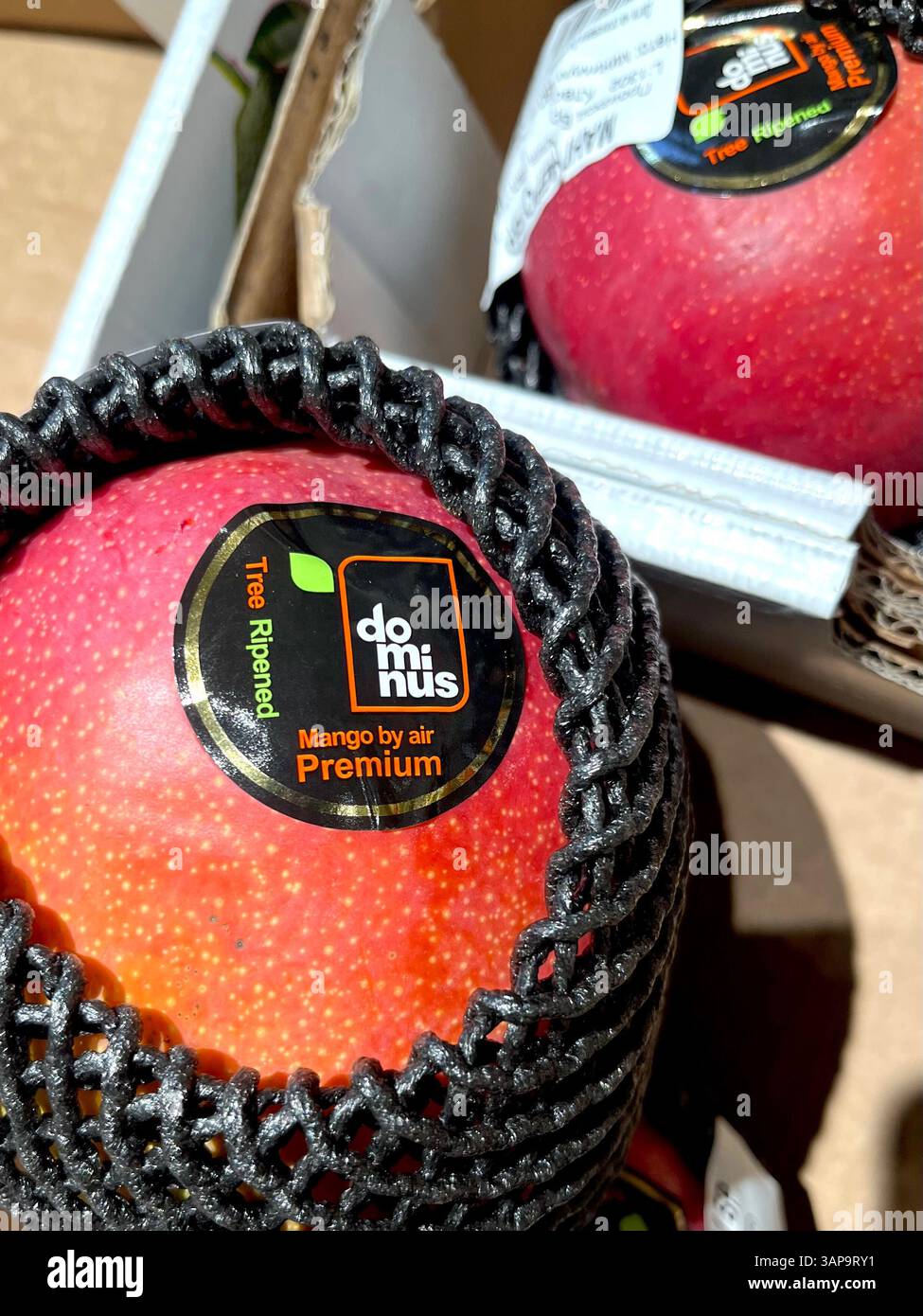 Premium Peruvian mango by Dominus, branded “Mango by Air,” wrapped in protective netting and marketed as a luxury tropical fruit. - Smartphone Captured Stock Image