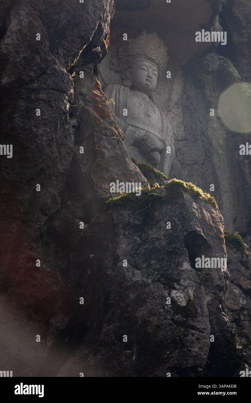 This is Guanyin Bodhisattva carved in the rock wall. Radiating light, she overlooks all beings and listens to their voices, embodying mercy and compas Stock Photo