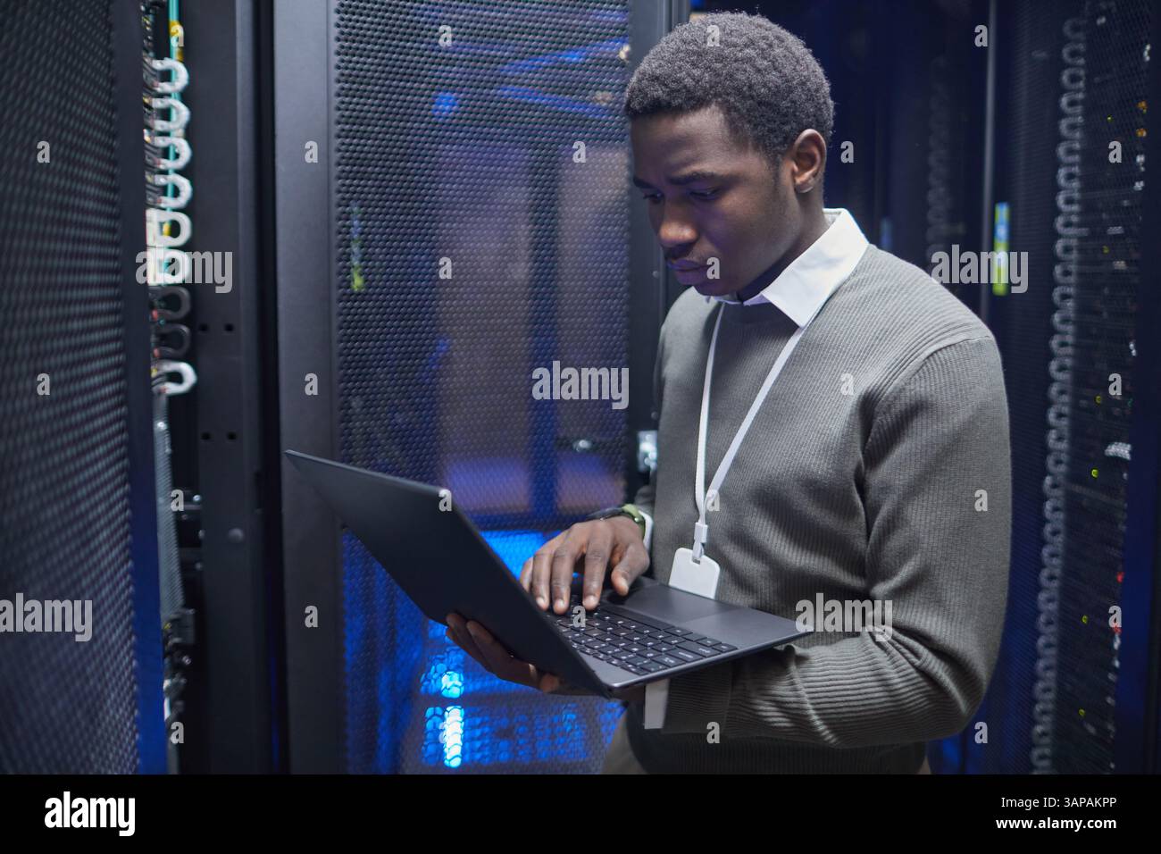 Technician working on configuring server racks inside modern data center, ensuring system functionality and network connectivity Stock Photo