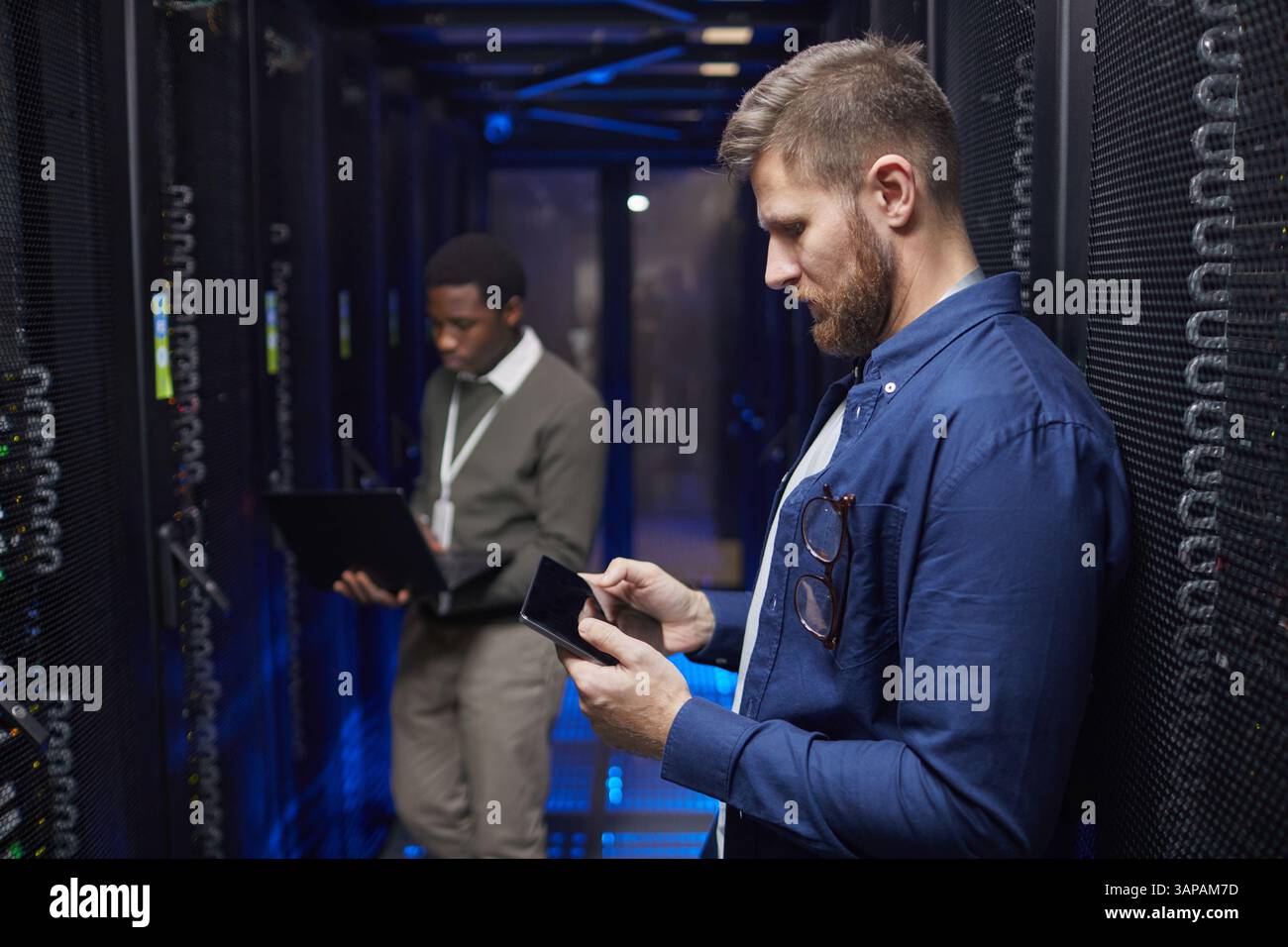 Engineers working in a modern data center server room, checking devices