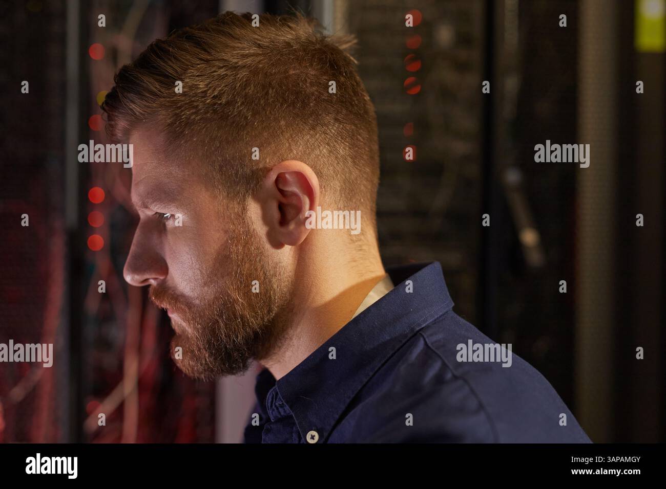Man with beard intently examining server racks in a data center wearing ...