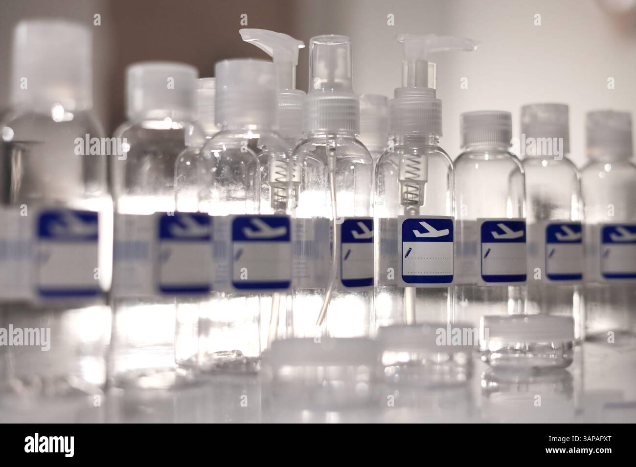 Small, transparent, plastic liquid bottles for plane traveling. Blank label with blue plane icon. Stock Photo
