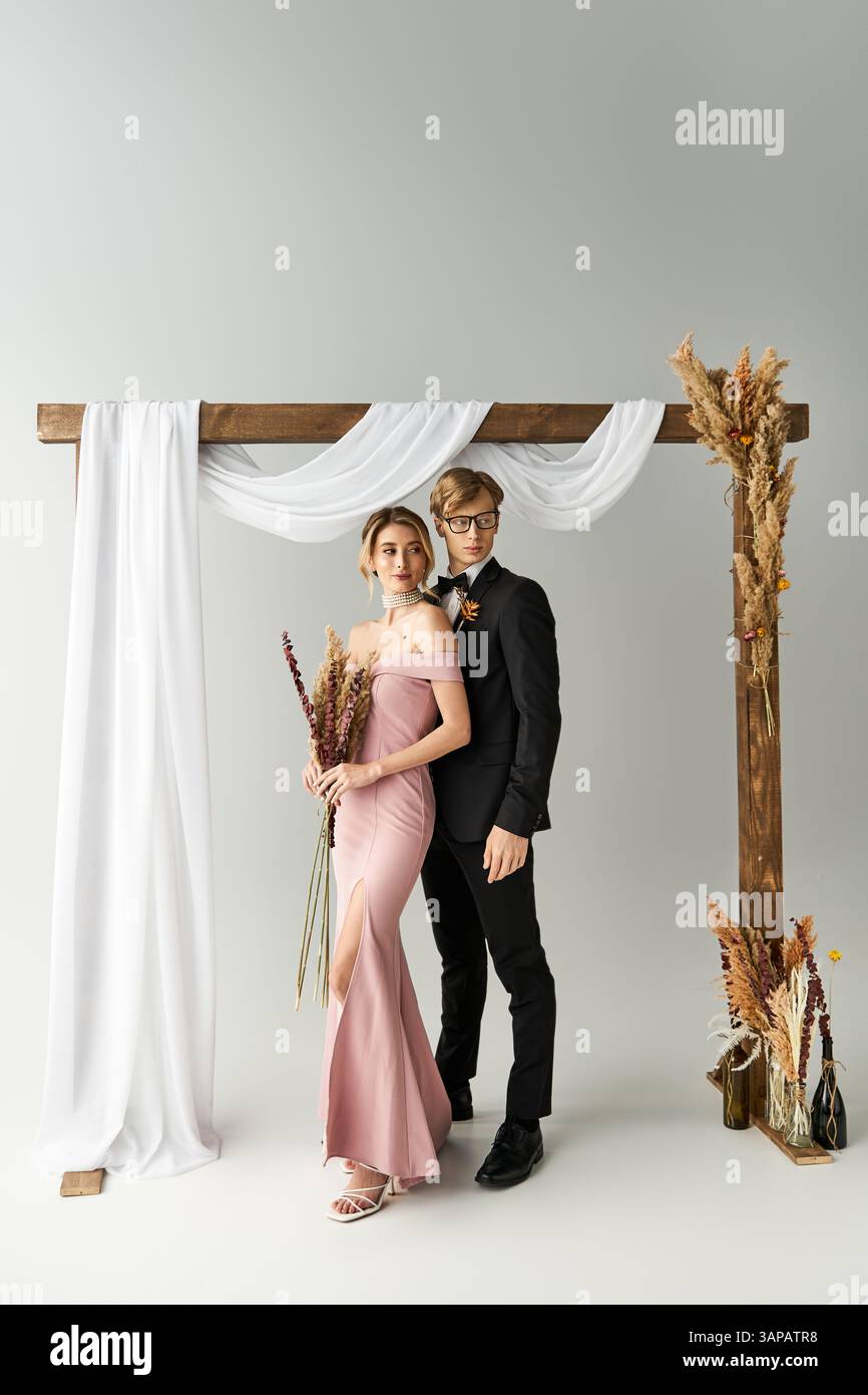 A happy couple under a decorative arch, celebrating their elegant spring wedding. Stock Photo