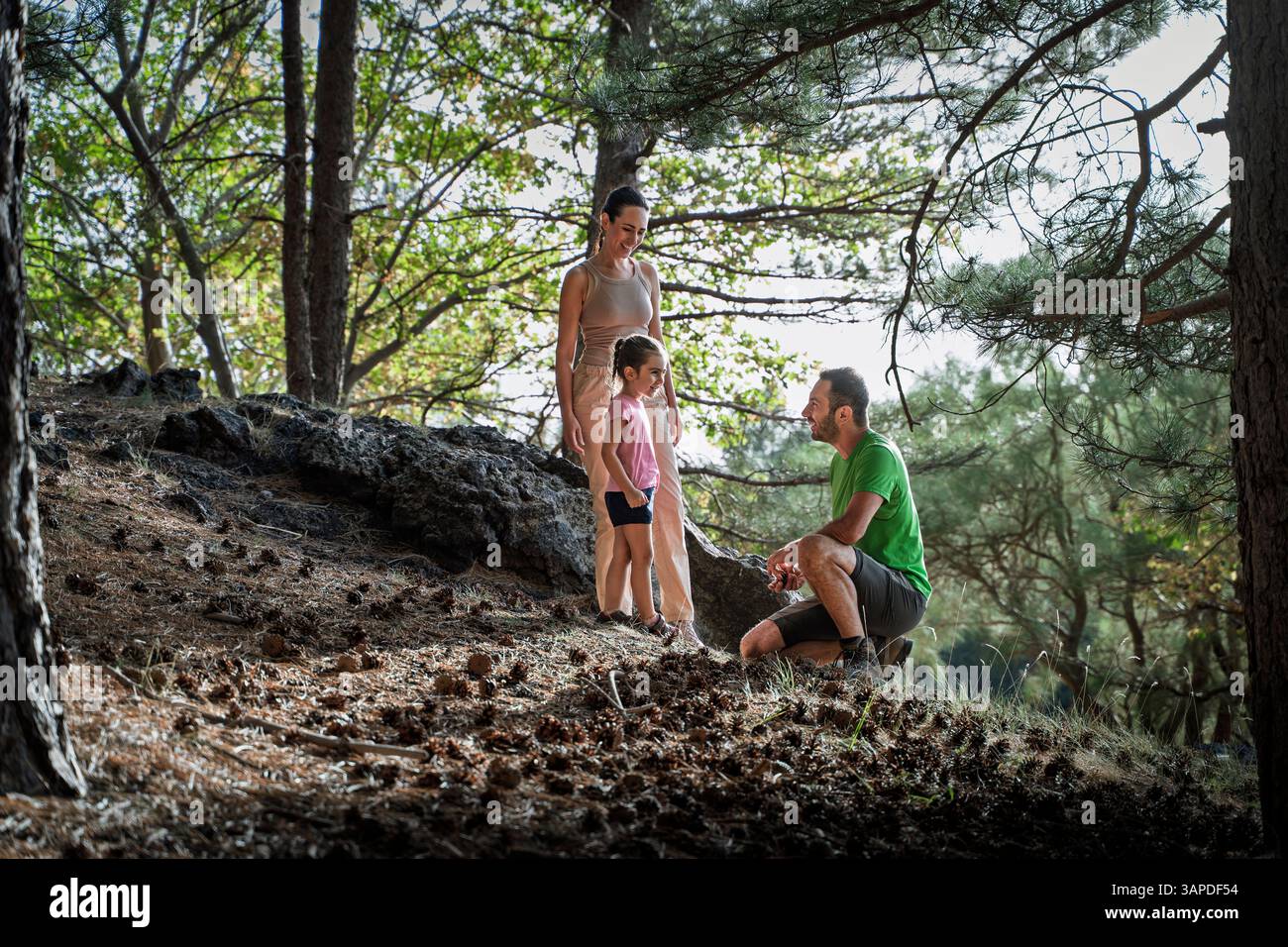 Father kneeling and talking to daughter in the forest while mother ...