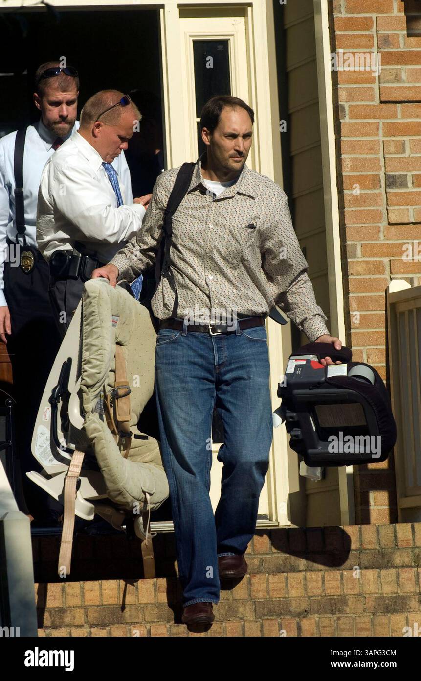 BRAD COOPER, front, is escorted out of his house by Cary police detectives after an autopsy report came back identifying his wife Nancy Cooper as the body that was discovered Monday night in a pond in Cary. Cooper had been reported missing since Saturday morning when she left her Lochmere home to go running. Stock Photo