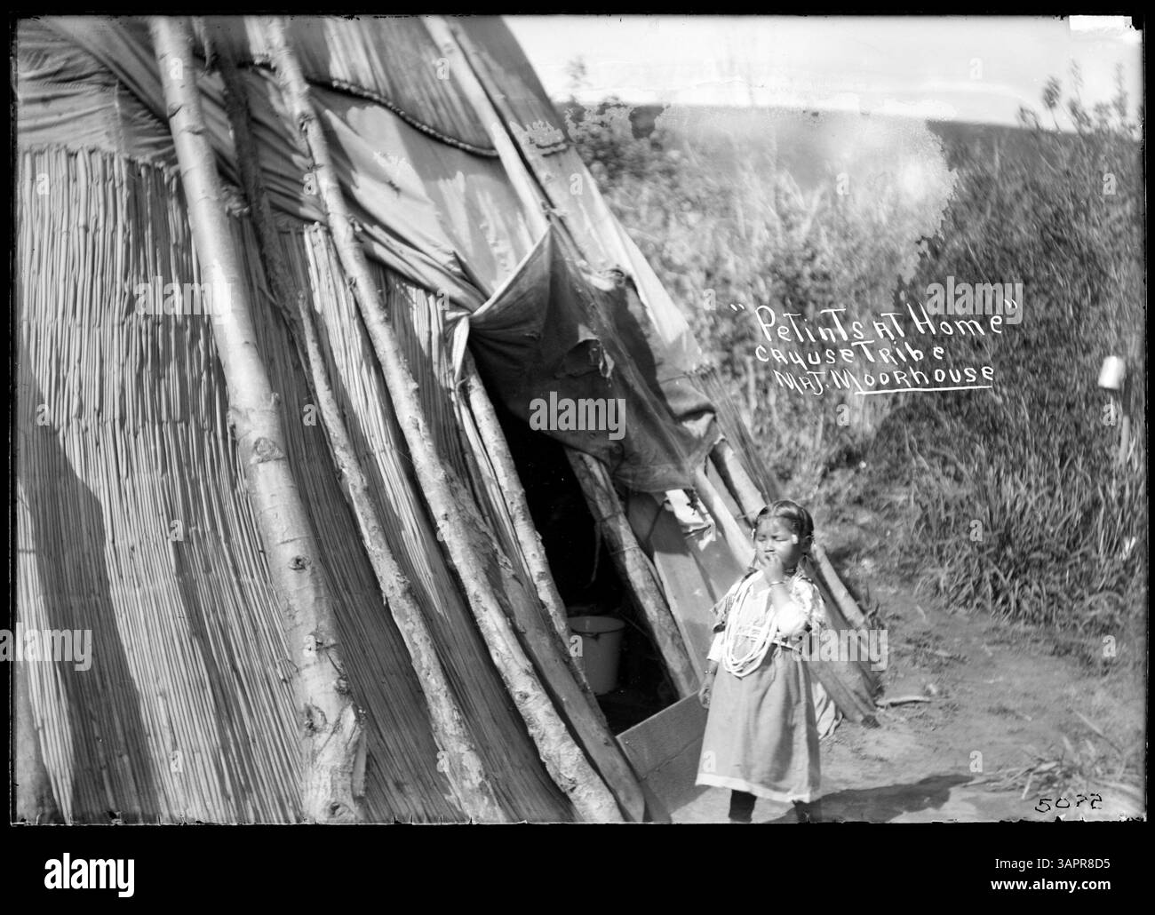This photograph depicts Petints, a Cayuse child, standing outside a ...