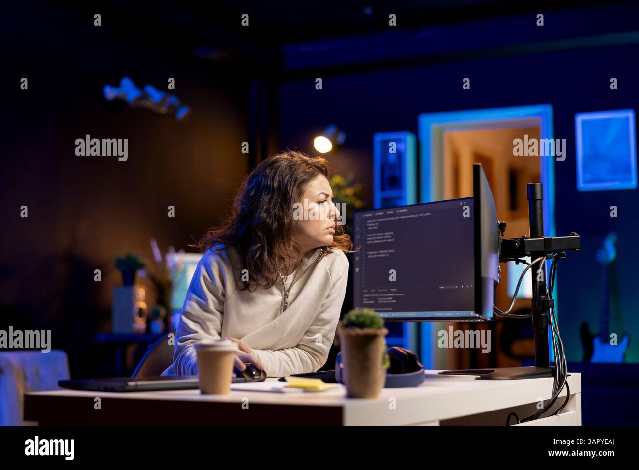 System administrator doing software debugging on PC at home, checking broken lines of code displayed on monitors. Proficient IT specialist in apartment fixing coding problems, typing on keyboard Stock Photo