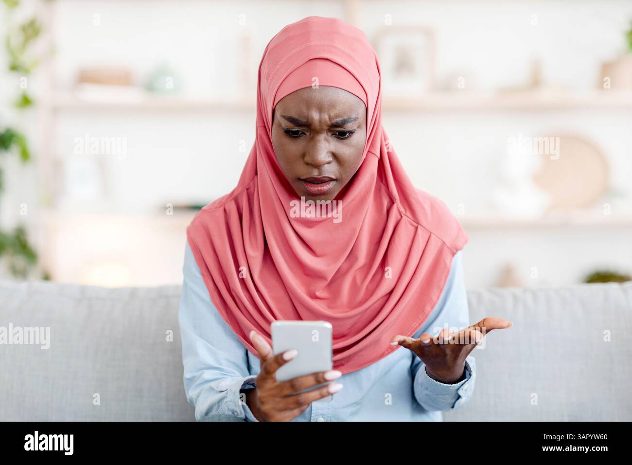 Shocked Black Muslim Woman In Hijab Looking At Cellphone Screen At Home ...
