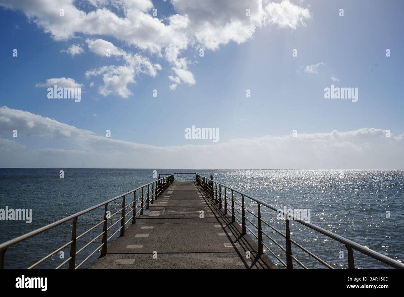 Scenic ocean view from a concrete pier with metal railings extending ...