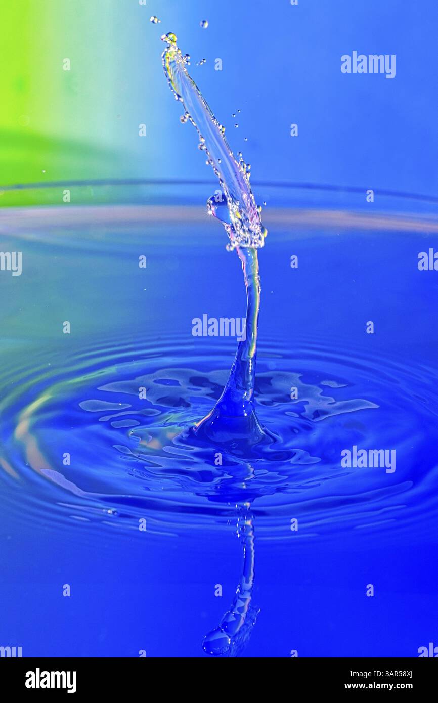 An elegant blue water drop rises from a water surface, water drop ...