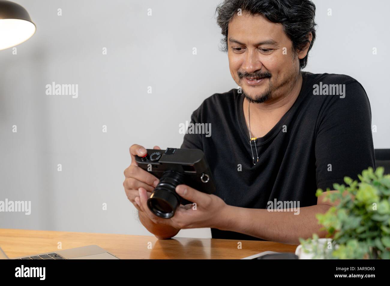 A young male photographer working from home, editing photos on his laptop Stock Photo